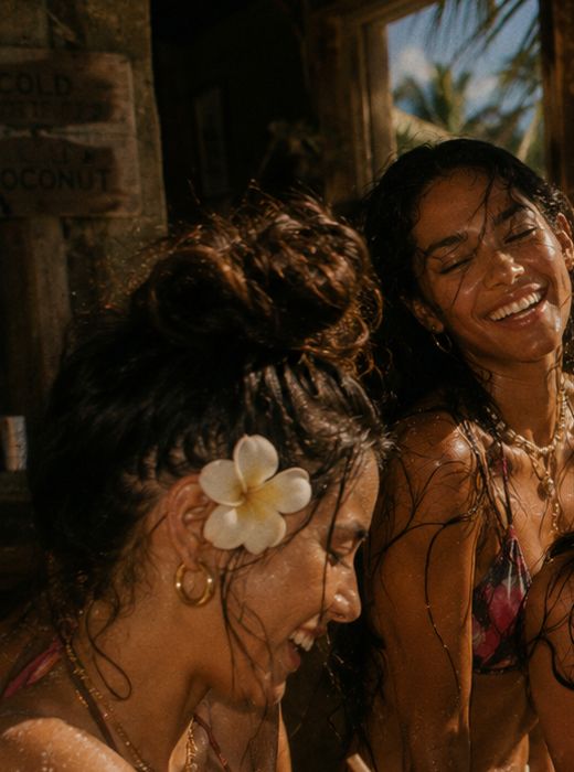 Two Aloha Girls laughing together, plumeria in her hair