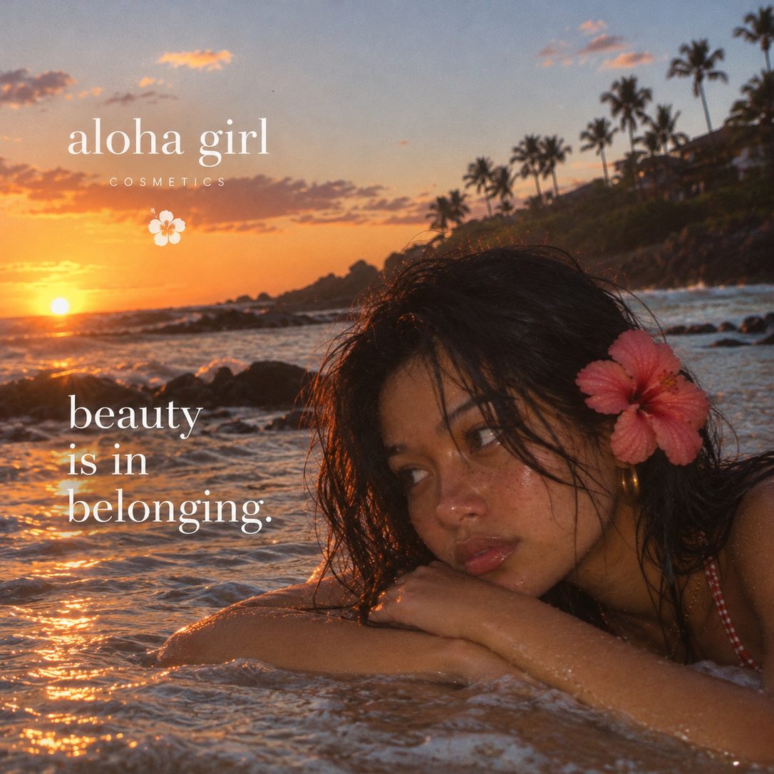 An Aloha Girl resting her head on her arms at the water&rsquo;s edge at sunset, a hibiscus in her hair, with the words beauty is in belonging