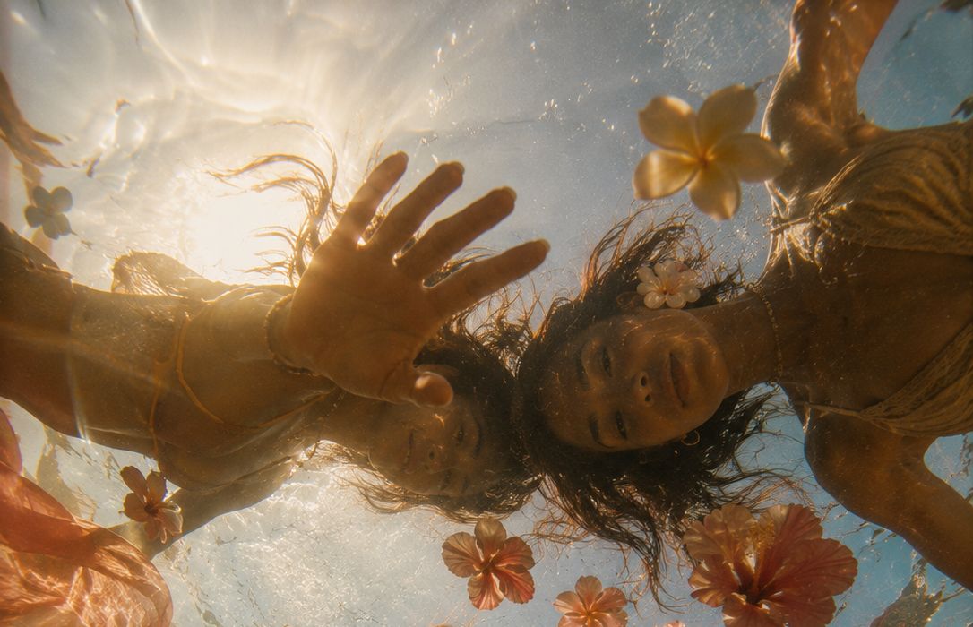 Aloha Girls floating together underwater, hibiscus and plumeria drifting in the sunlight